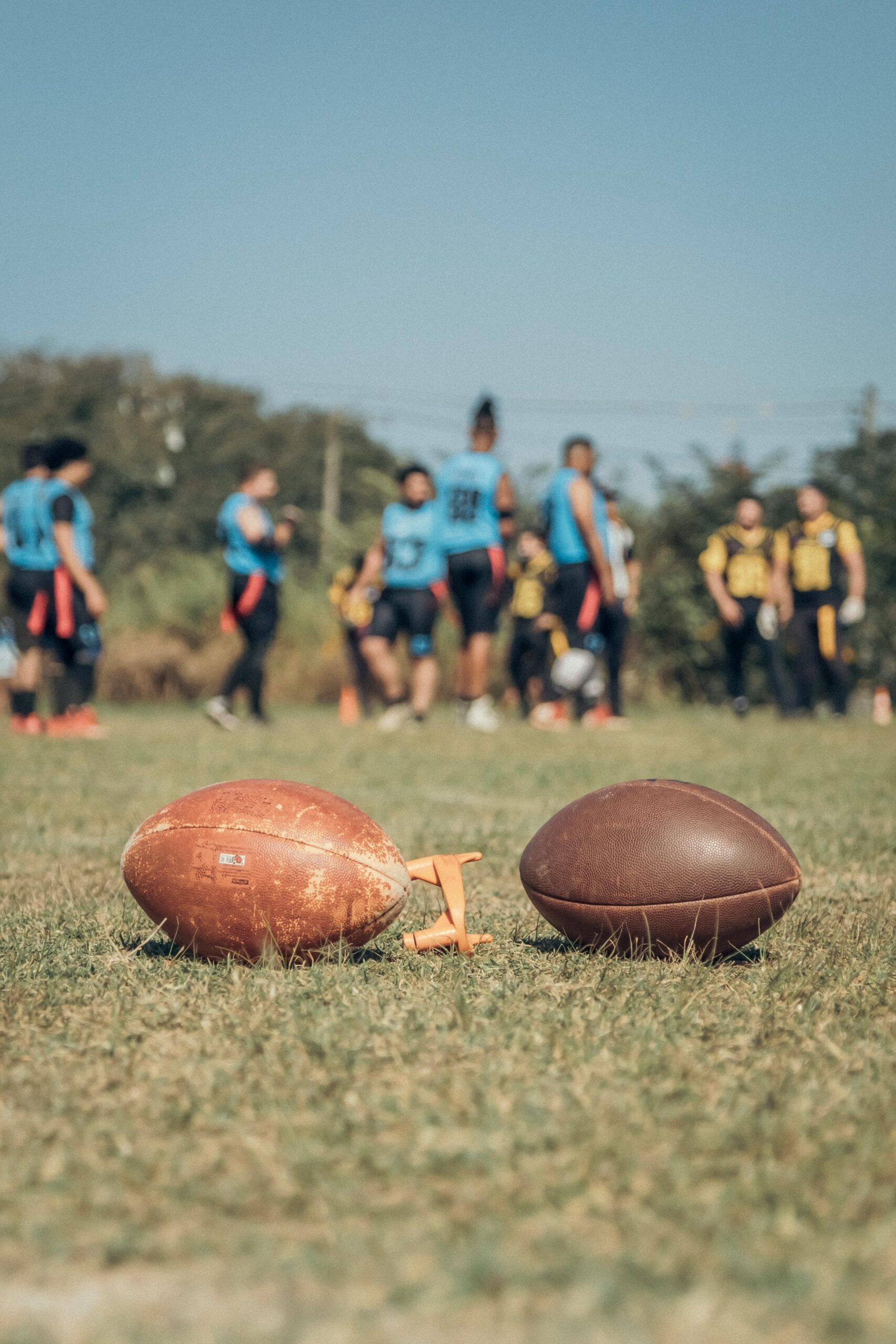 American football game with players and balls on green field outdoors.